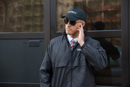 Caucasian Security Officer in Uniform Leading Group of Event Staff on Surveillance Patrol for Building Protection